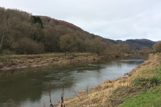 A river in Wales, with a wooded hill on the far bank