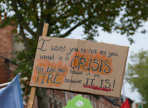 A sign at the climate march reads "I want you to act as you would in a crisis. Act like our house is on fire because it is!"