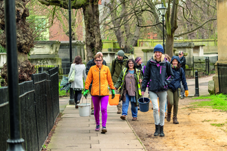 Group of people walking in London with gardening equipment in late winter