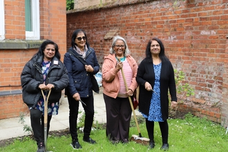 Four women standing with gardening equipment