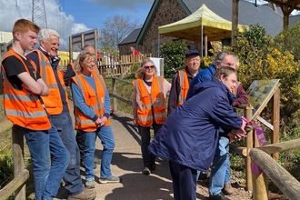 Volunteers in hi-vis jackets gather in a community garden. 