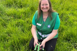 Woman sitting on the grass holding gardening tools