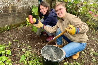 Two young people harvest potatoes on a small patch of garden. 