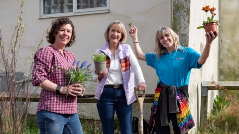 Three people holding plants