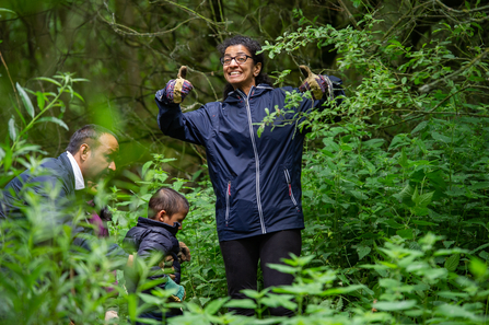 Family in woodlands. Woman smiling towards camera with 'thumbs up'