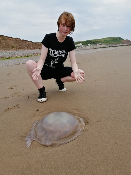 Marsh young volunteer award winner Cat Bell on a beach with a jellyfish