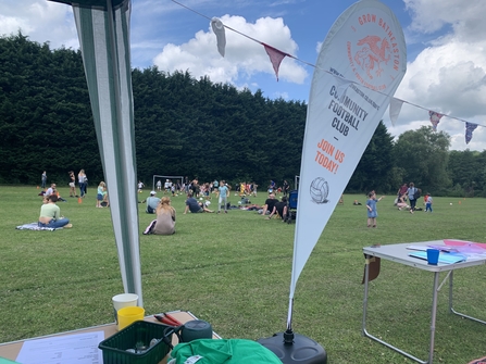 View from a gazebo of people playing and watching football in a park. 