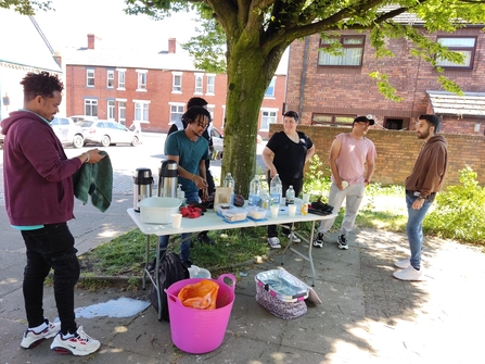 A group of volunteers serve themselves refreshment outside.