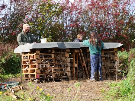 Young people build a large bug hotel. 