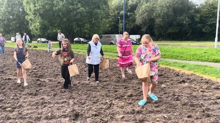 Parents and childred sow wildflower seeds