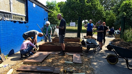 Group of people build raised beds. 