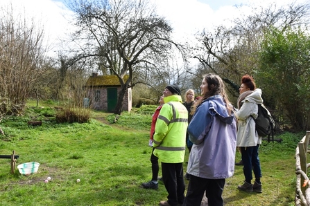 Group of people gather in a green space with trees in the background