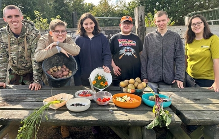 Young people stand behind a table filled with fresh vegetables