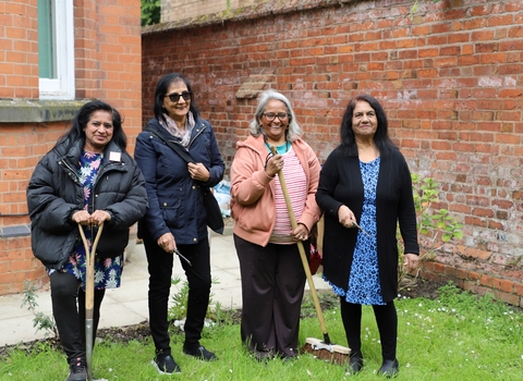 Four women standing with gardening equipment